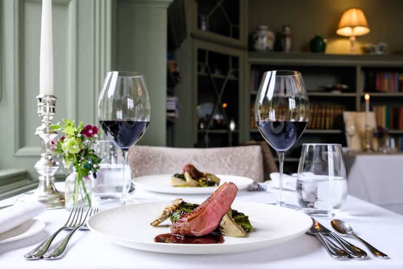 Restaurant table with wine and a seasonal dish in The Library at Douneside House