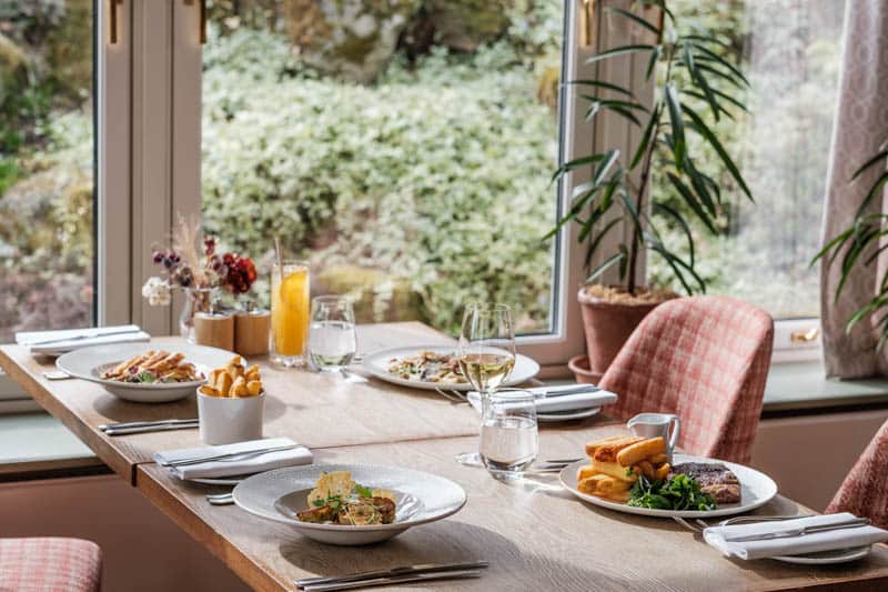 Table prepared for dining beside the garden windows in The Conservatory