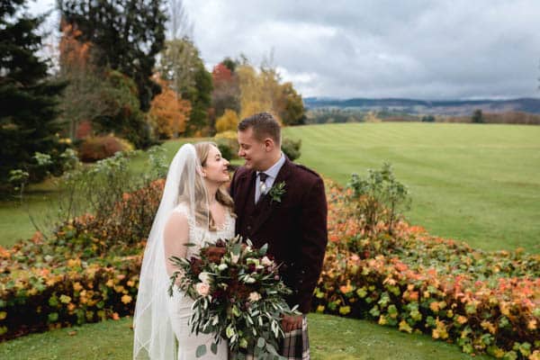 Standing together in the gardens on their wedding day