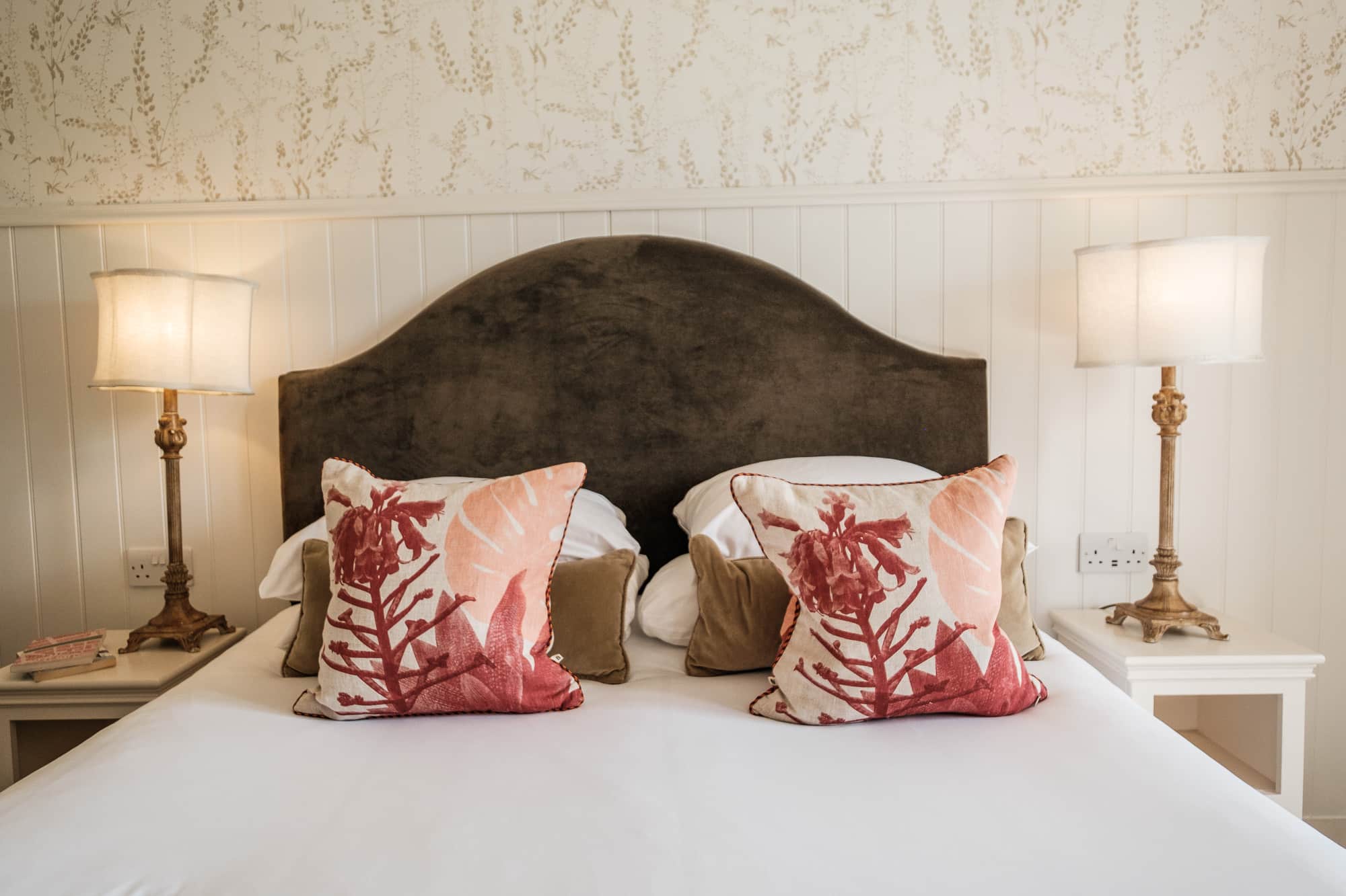 Double bedroom in Pine Cottage with botanical wallpaper, wicker chair and framed prints at Douneside House