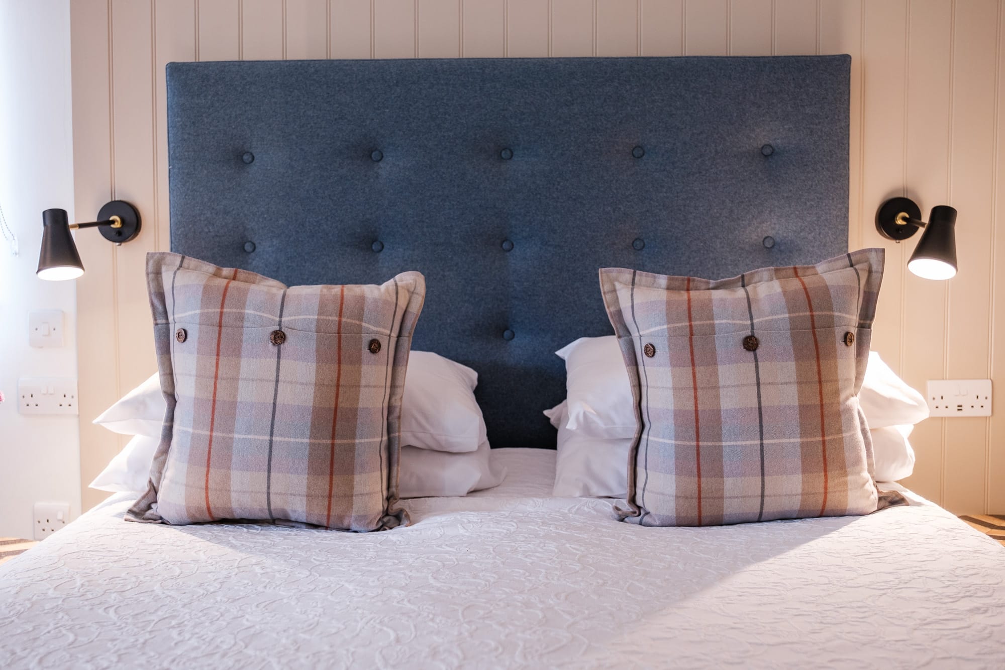 Casa 22 bedroom detail with tufted headboard, tartan cushions and reclaimed wood side table at Douneside House