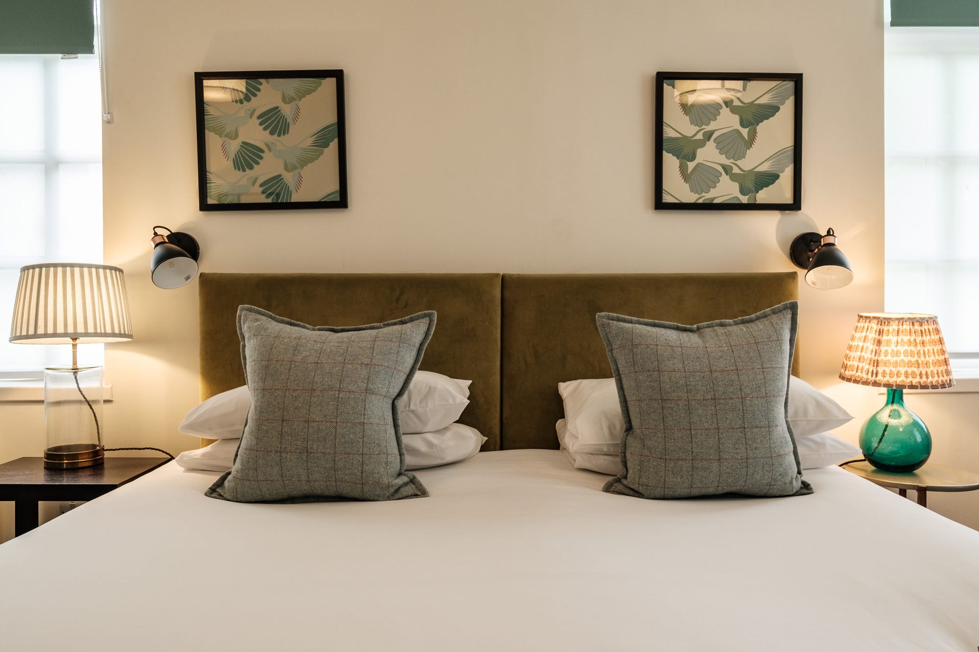 Morven Cottage bedroom detail with olive velvet headboard, tweed cushions and bedside lamps at Douneside House