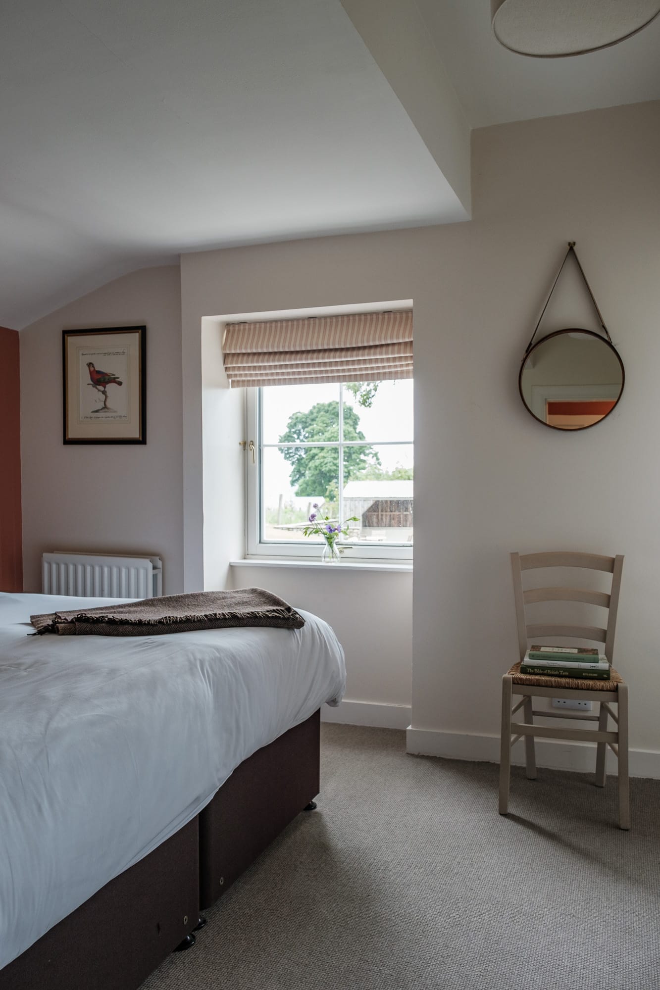 Bedroom with view Bedroom in Alpha Cottage with countryside view, round hanging mirror and parrot print at Douneside House
