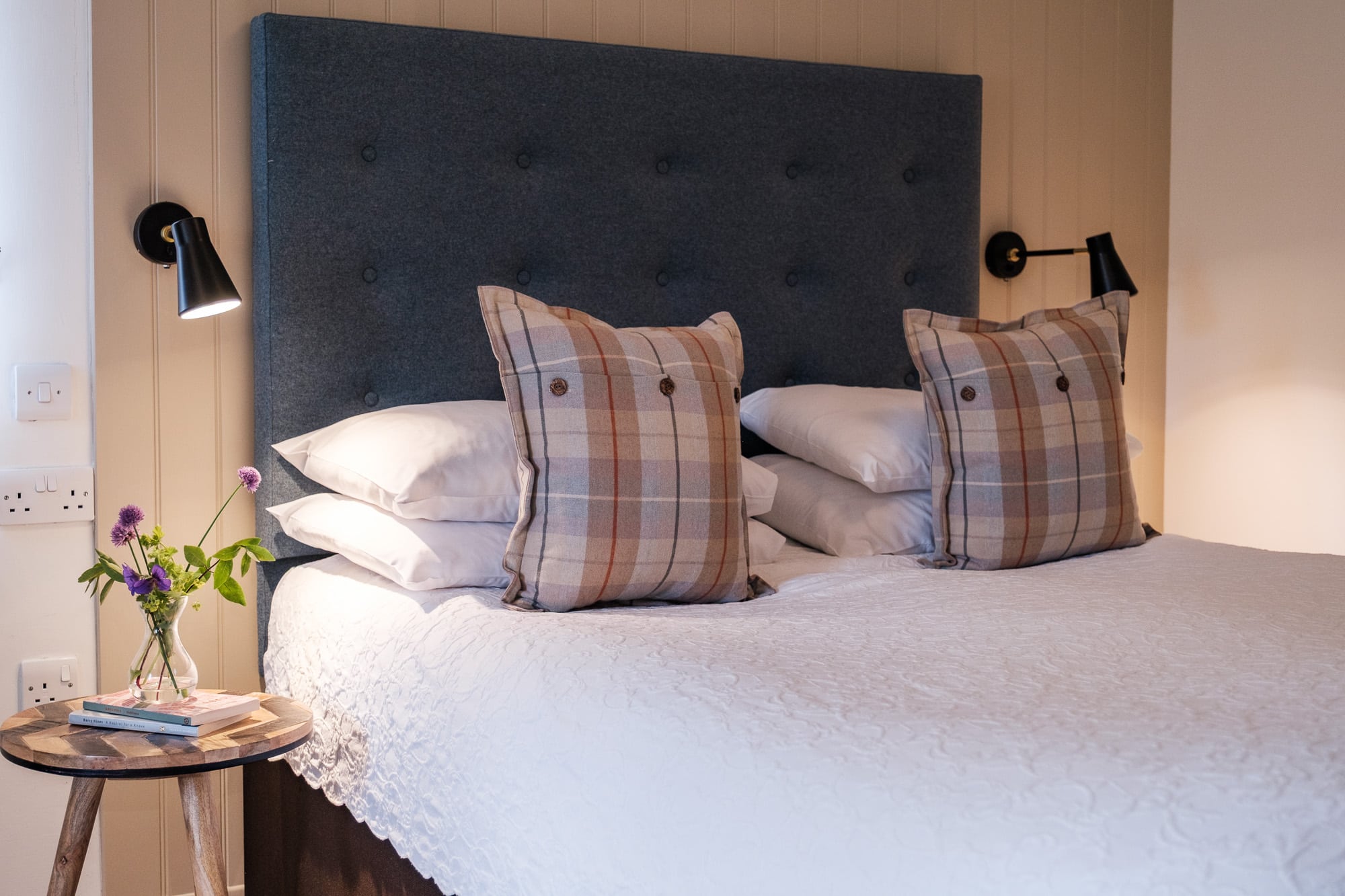 Casa 22 bedroom with navy headboard, tartan cushions and bedside stool at Douneside House