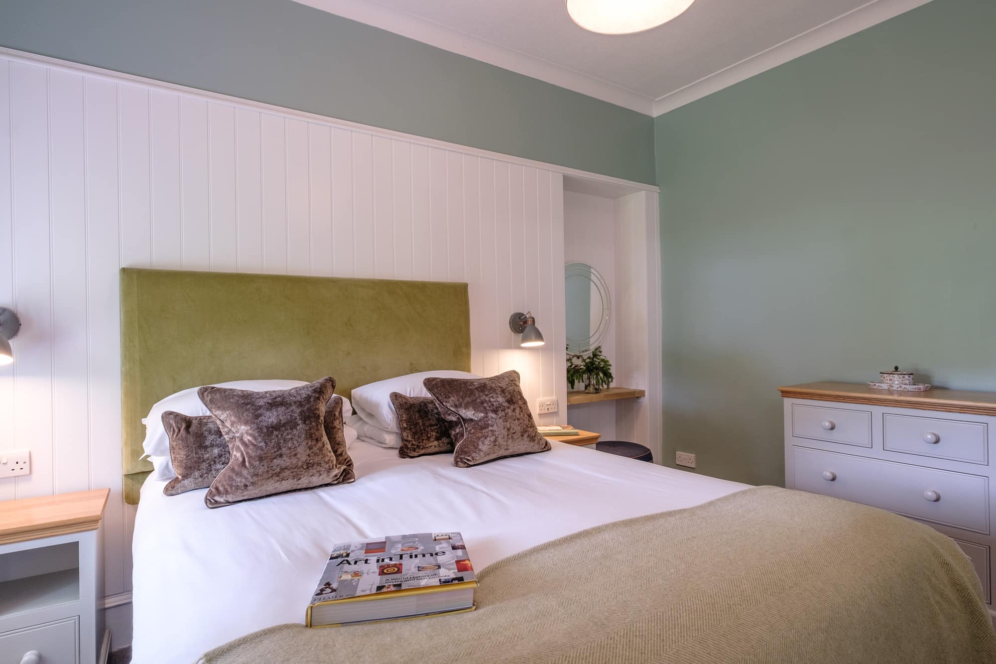 Gatehouse bedroom with green velvet headboard, sage walls and panelled dressing nook at Douneside House
