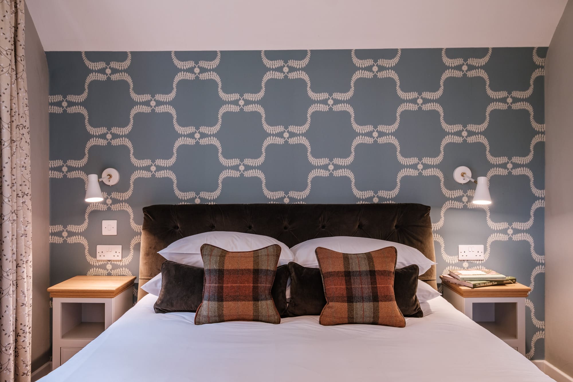Casa 24 bedroom detail with tufted velvet headboard, tartan cushions and blue wallpaper at Douneside House