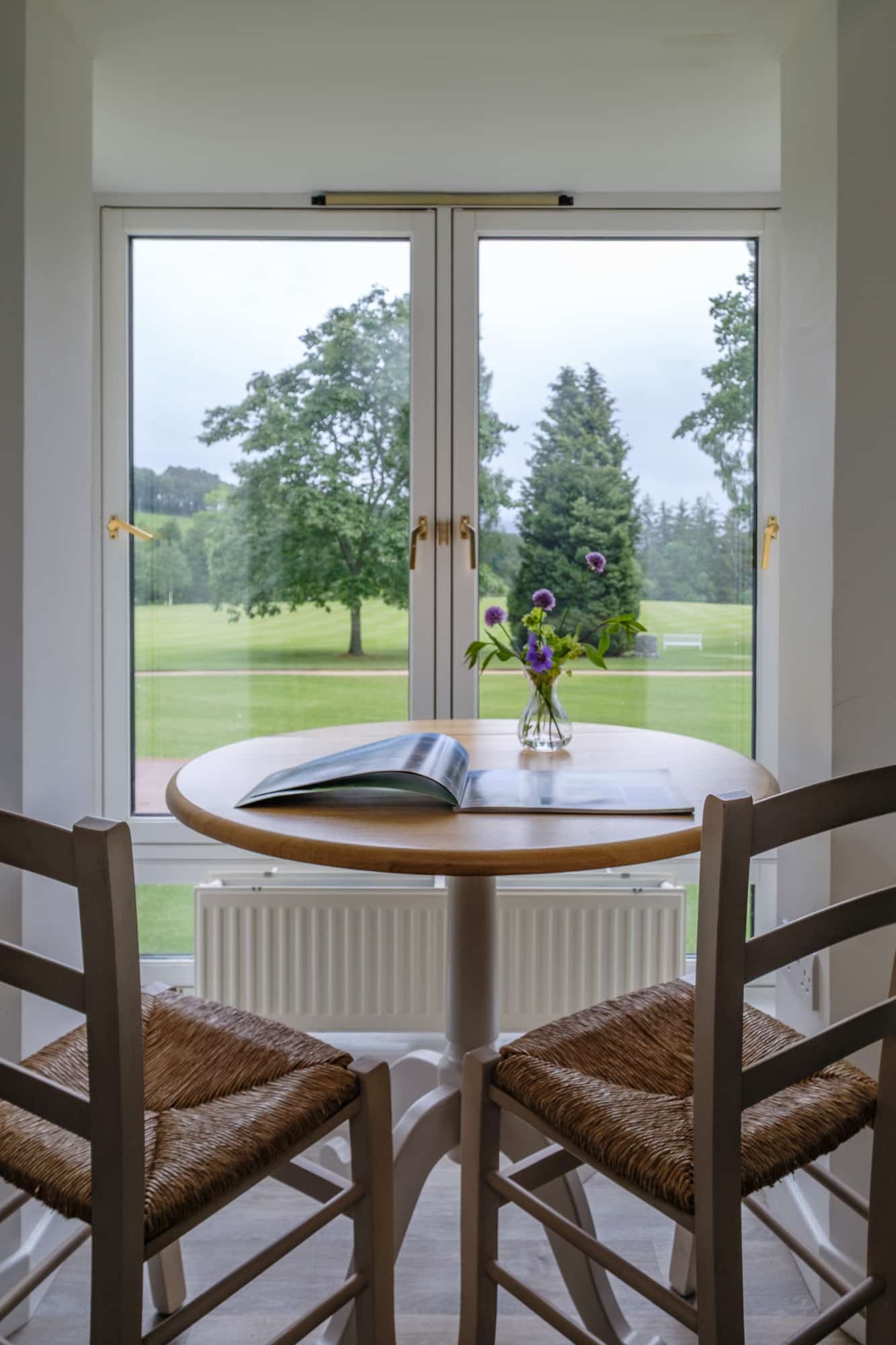 Casa 22 dining table with rush chairs and view over Douneside House gardens