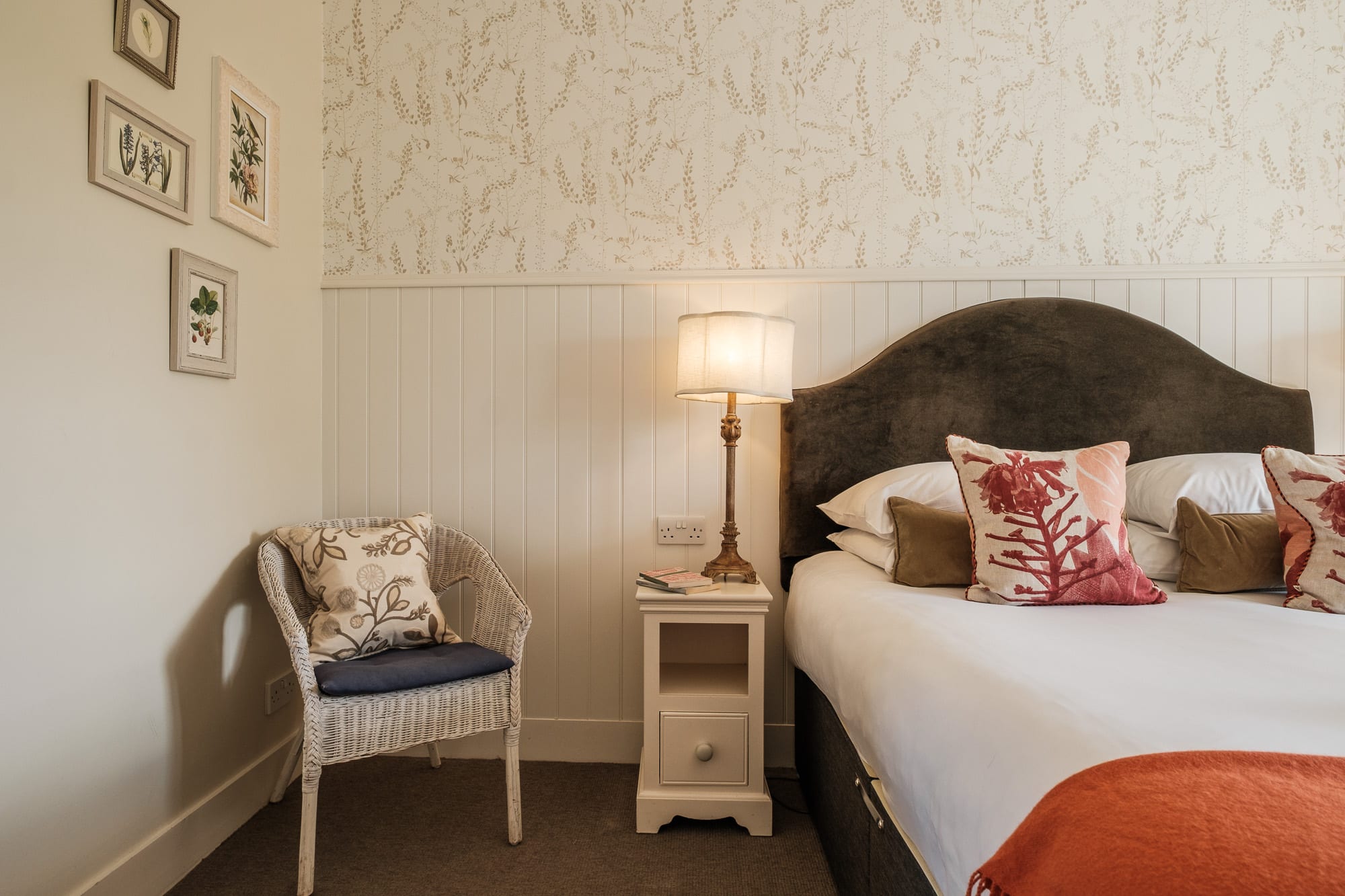 Double bed in Pine Cottage with velvet headboard, botanical cushions and matching lamps at Douneside House