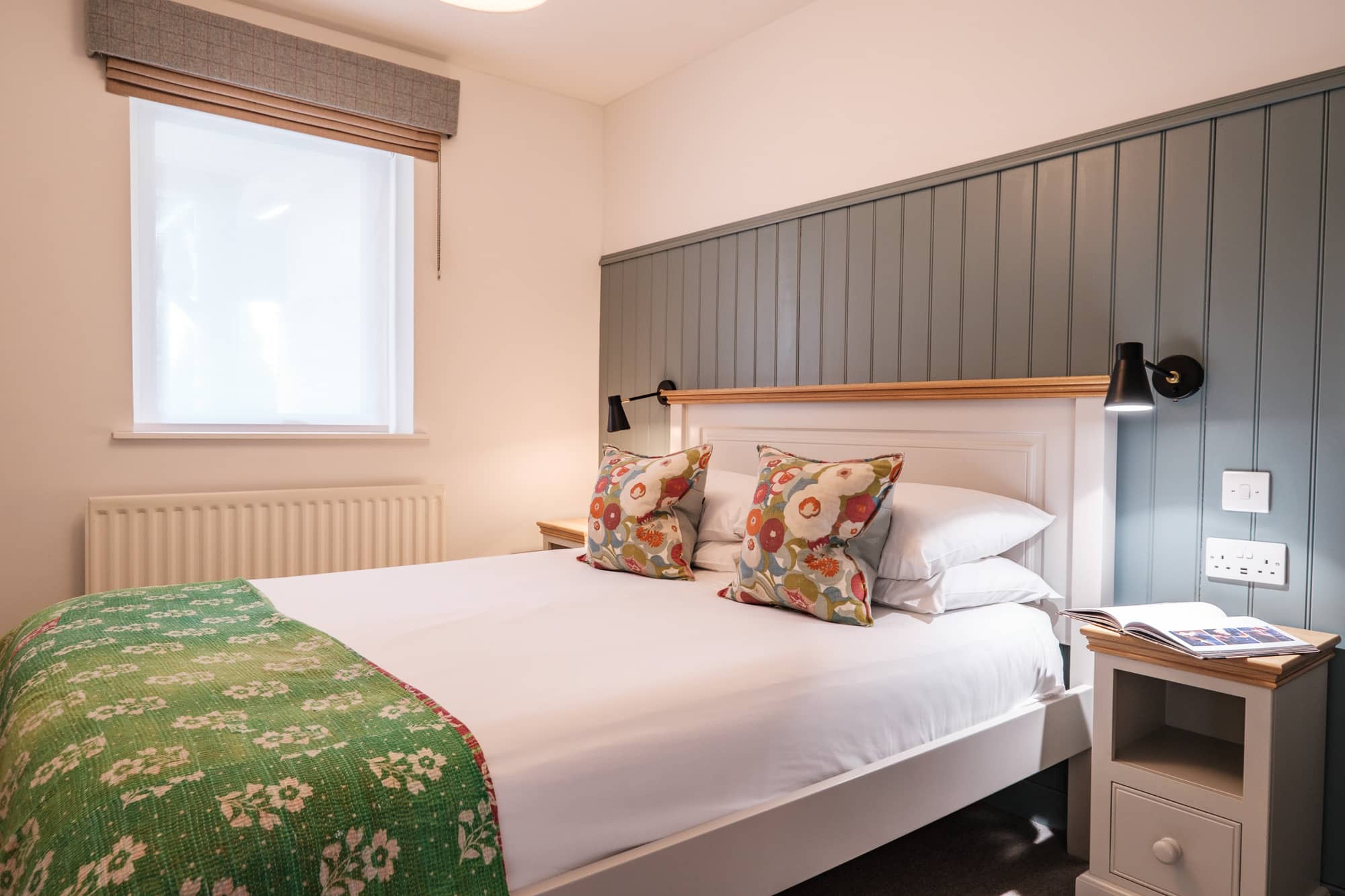 Double bedroom in Casa 23 with sage panelled headboard wall and floral cushions at Douneside House