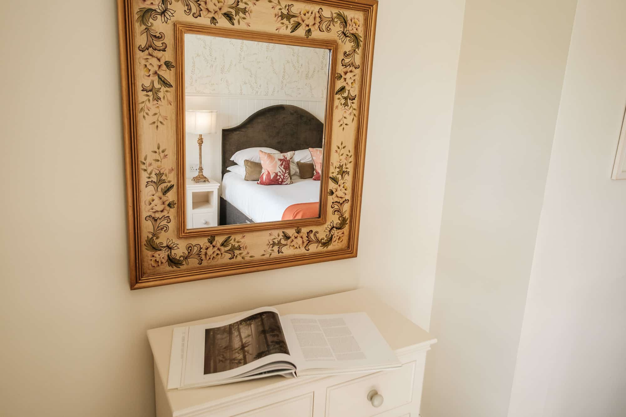 Painted floral mirror above white dresser in Pine Cottage bedroom at Douneside House