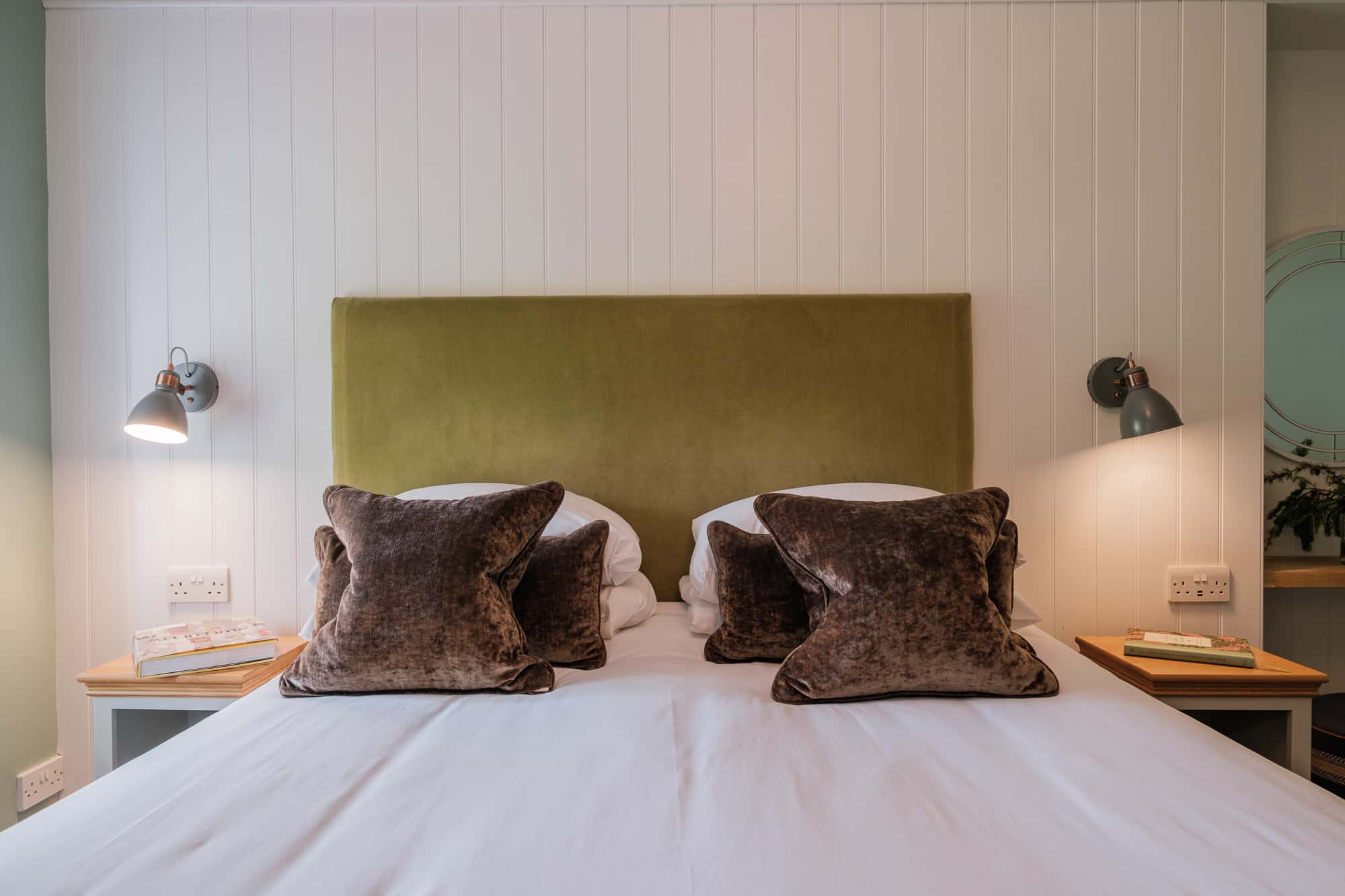 Gatehouse bedroom detail with green velvet headboard, brown velvet cushions and copper reading lights at Douneside House