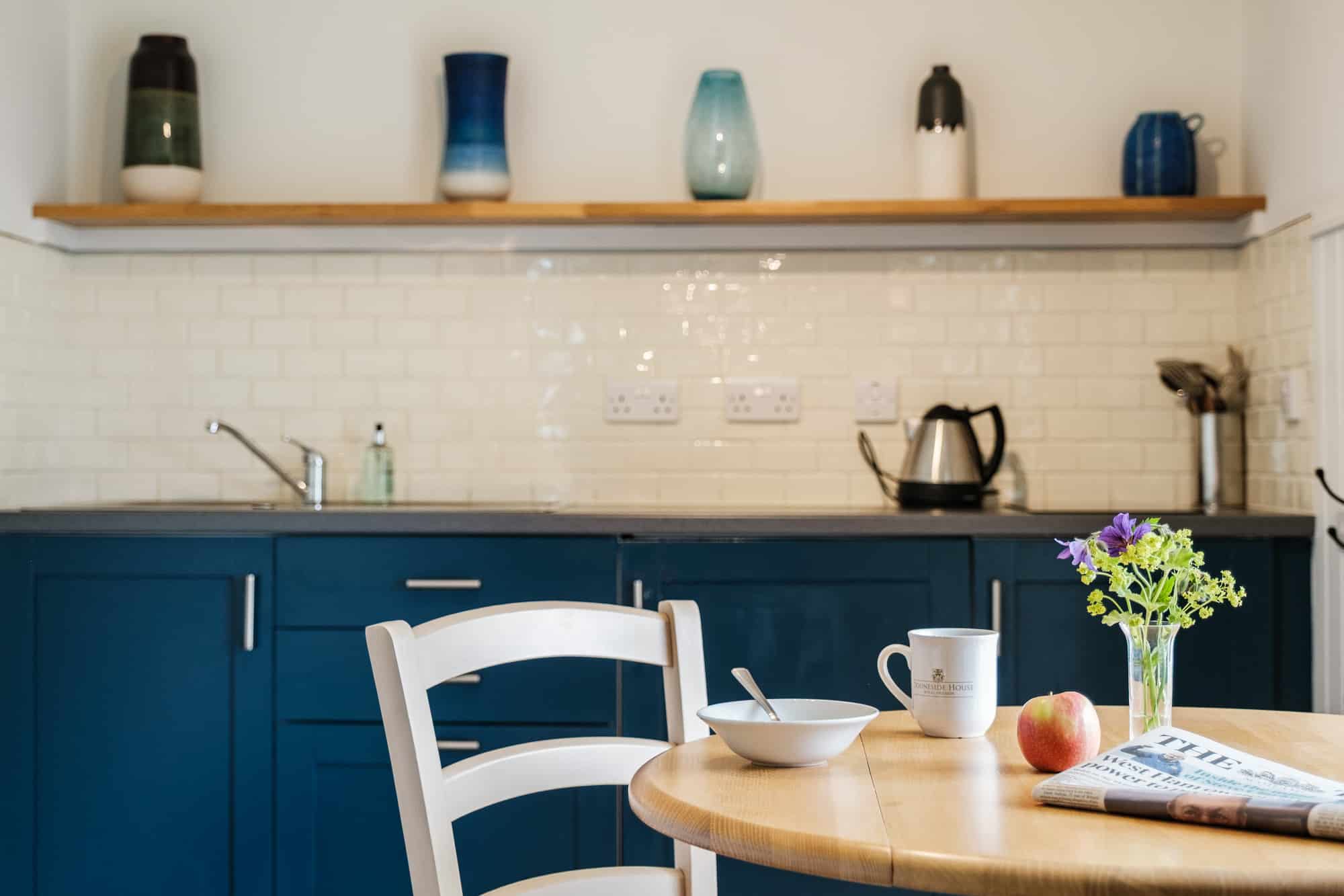 Kitchen in Casa 22 with navy cabinets, ceramic vase collection and branded Douneside House mug