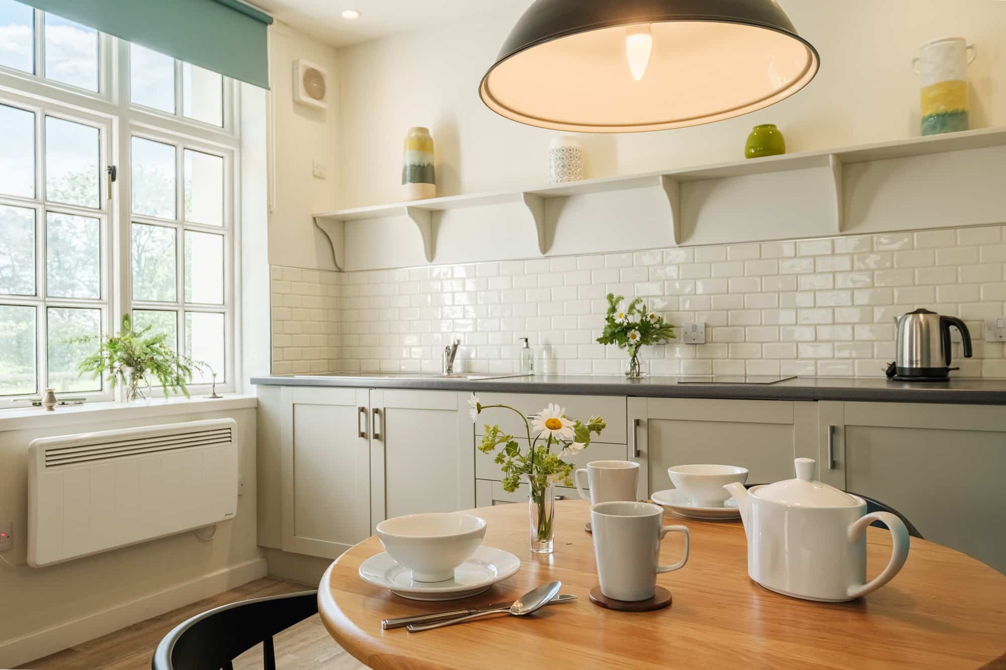 Kitchen in Morven Cottage with white shaker cabinets, metro tiles and oak dining table at Douneside House