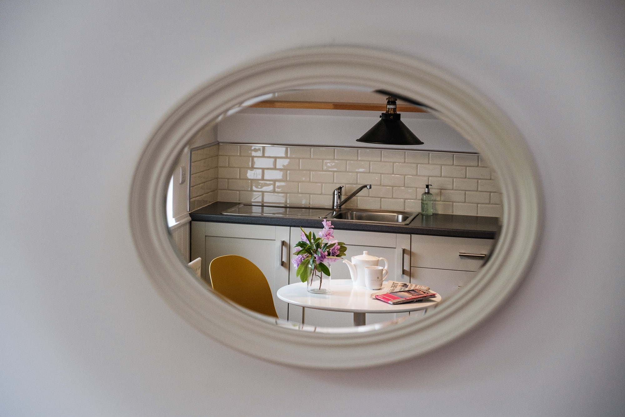 Casa 24 kitchen viewed through oval mirror with dining table and pendant lighting at Douneside House