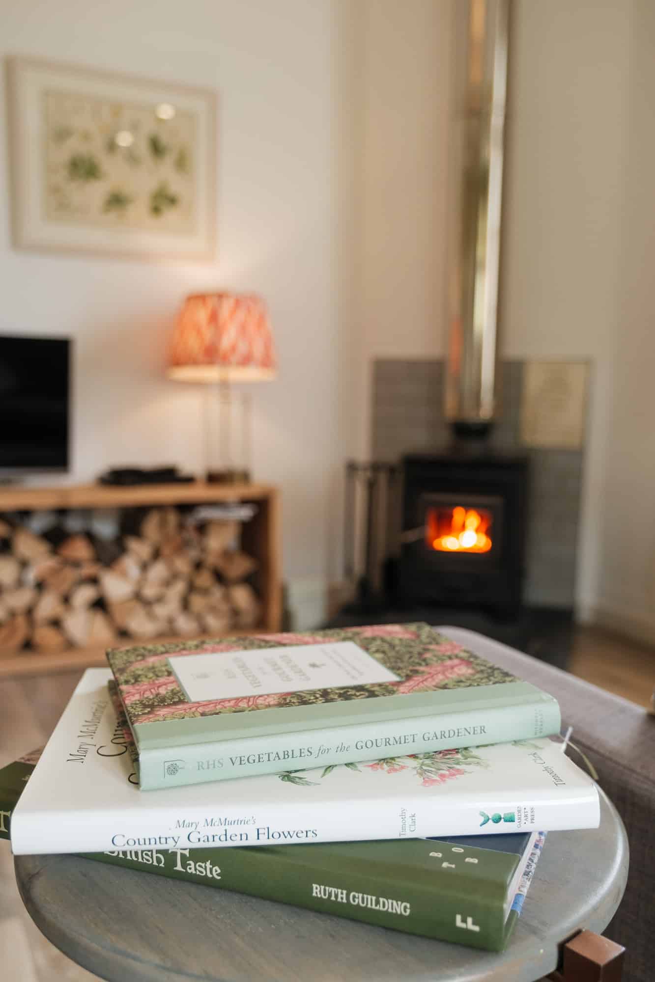 Living_Room_Dounebrae_Cottage Dounebrae Cottage sitting room detail with country books, lit wood-burning stove and stacked logs at Douneside House