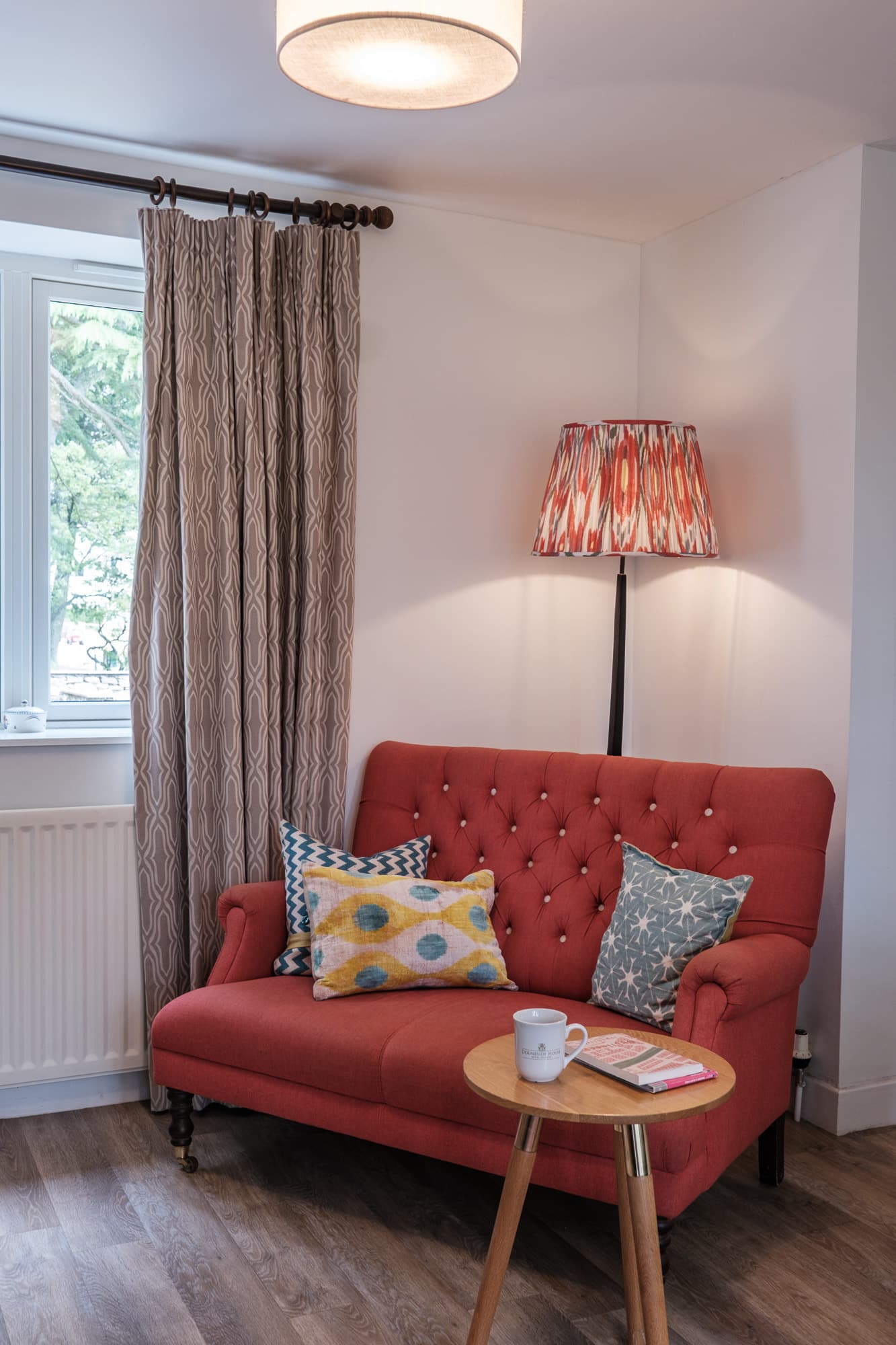 Living room seating in Casa 23 with red buttoned sofa and floor lamp at Douneside House
