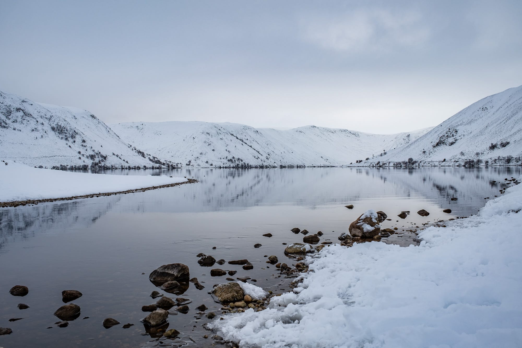 Loch Muik Snow-covered Loch Muick in the Cairngorms National Park, Royal Deeside, Aberdeenshire, surrounded by dramatic Highland mountains.