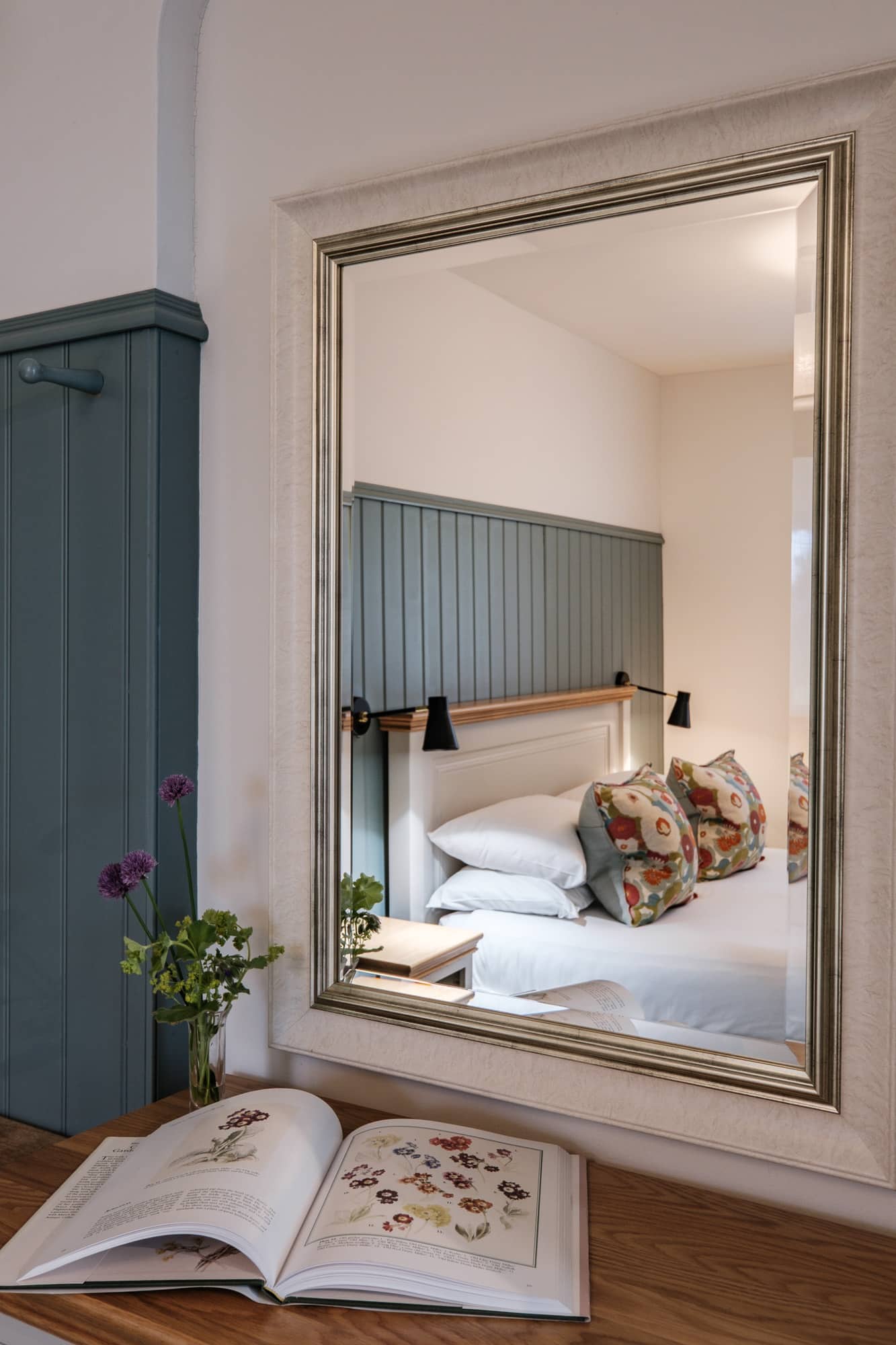 Reflection of Casa 23 Bedroom in dresser mirror with book and flowers at Douneside House Cottages