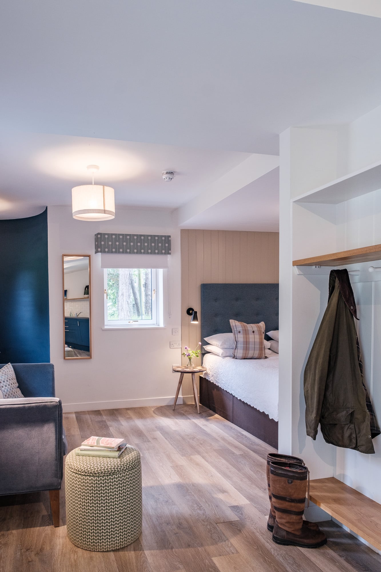 Casa 22 open-plan living and sleeping area with navy accent wall and hallway coat pegs at Douneside House