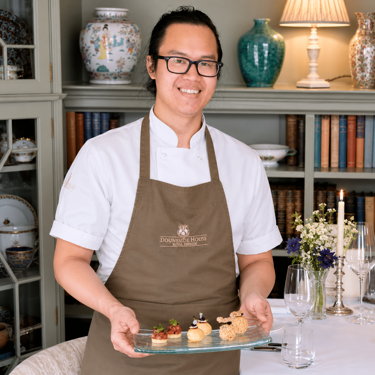 Smiling member of the Douneside House team wearing a hospitality apron