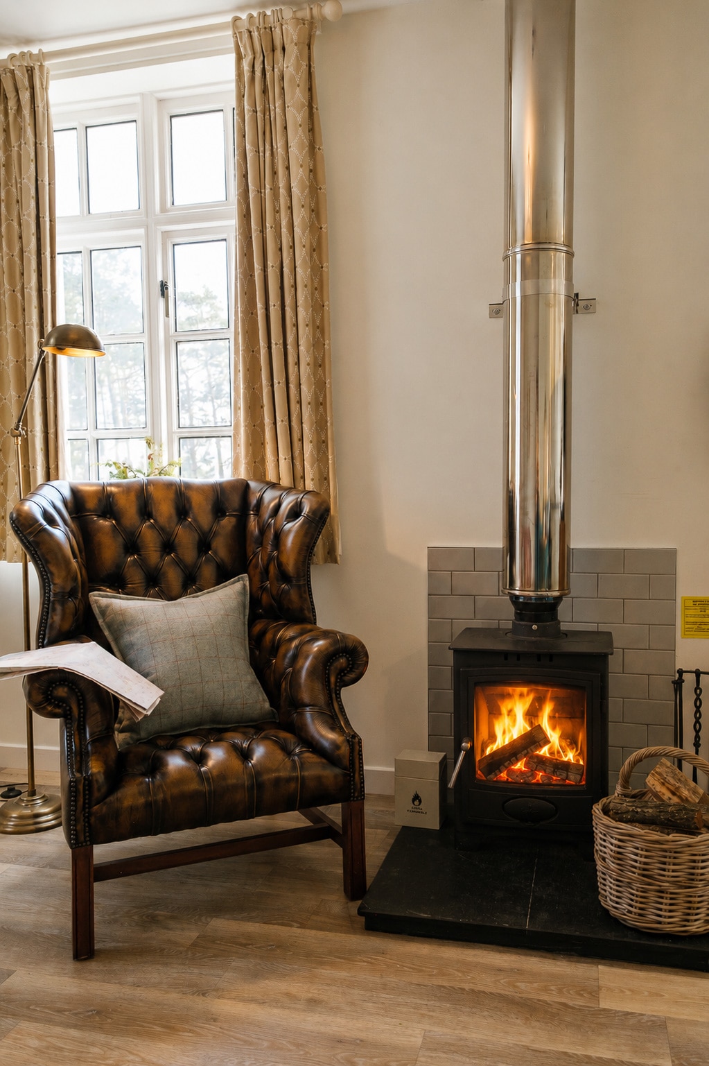 Fireside chesterfield wingback chair beside wood-burning stove in Morven Cottage at Douneside House